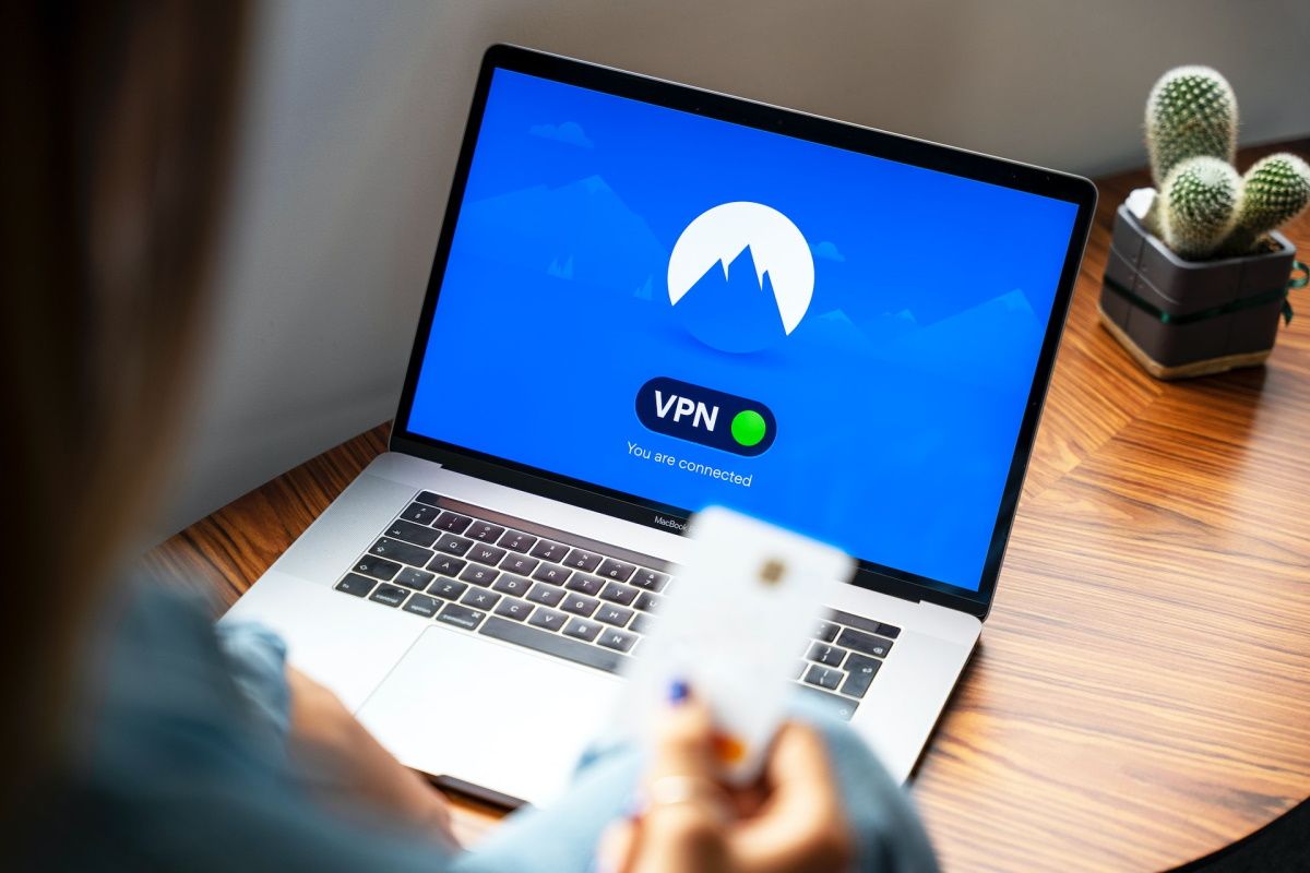 شخصی که یک کارت اعتباری با VPN متصل به لپ تاپ در دست دارد
