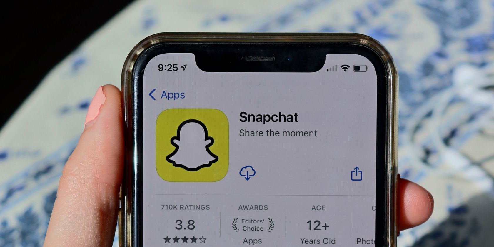 A hand holding a smartphone with a screen displaying the Snapchat logo