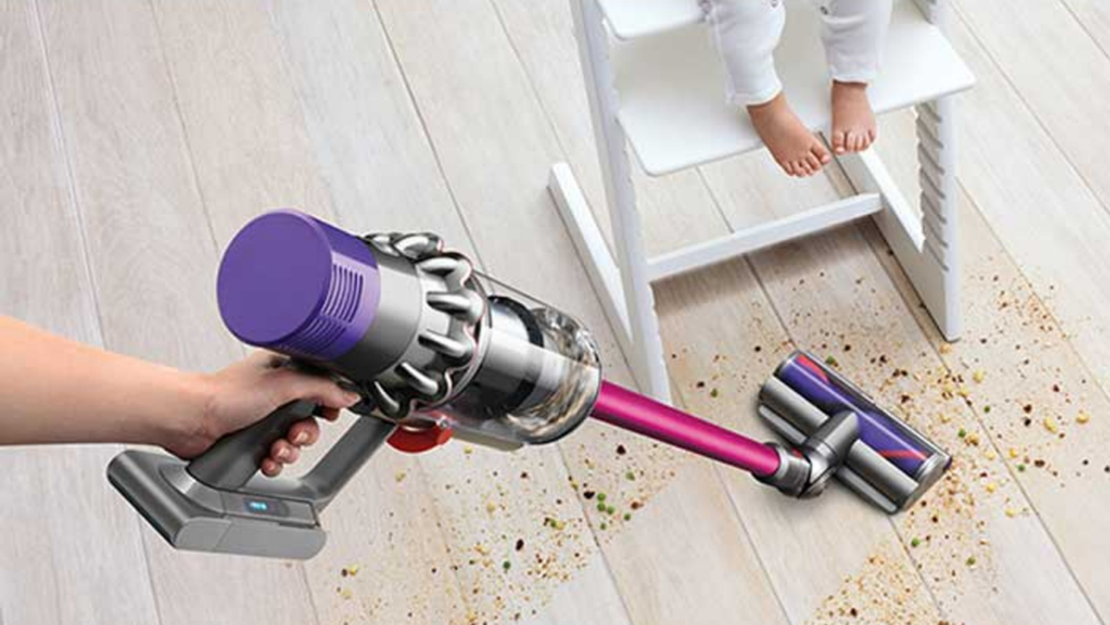 زنی که از Dyson V10 برای تمیز کردن آشفتگی روی یک کف چوبی استفاده می کند