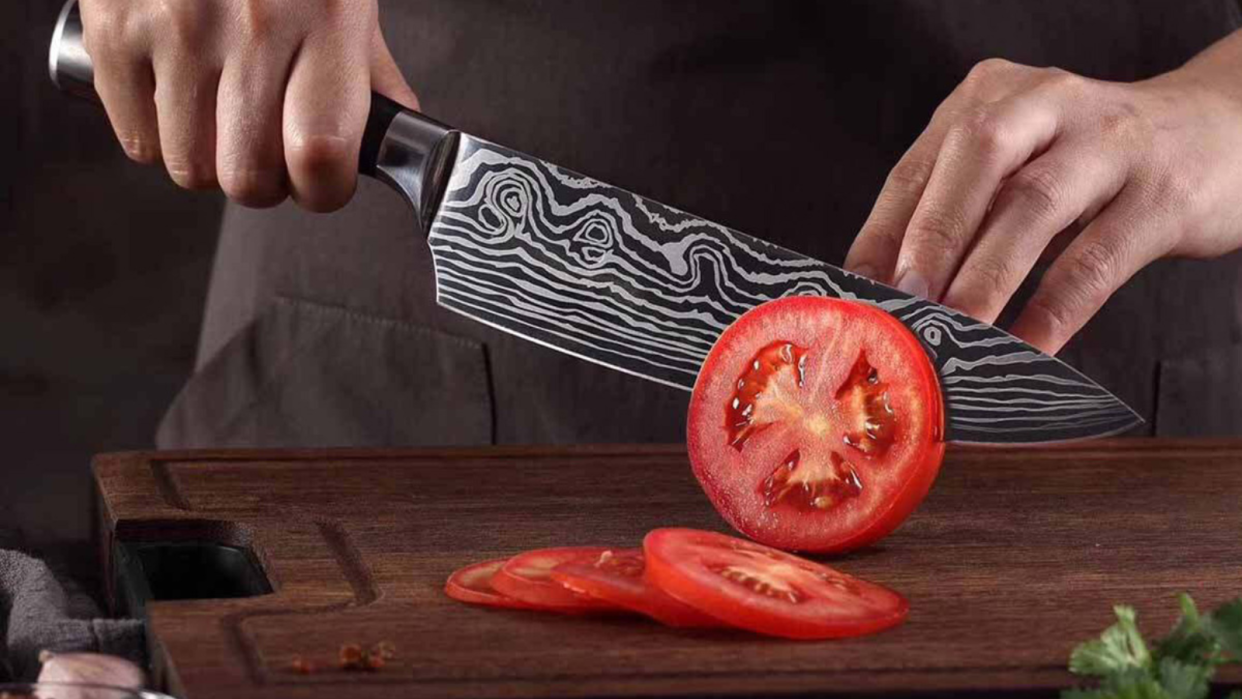 شخصی که از چاقوی آشپزخانه کونیگ برای برش دادن گوجه فرنگی استفاده می کند